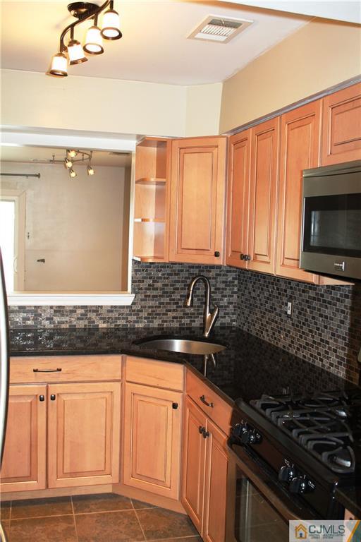 59 La Rue Lane, Unit 59 East Brunswick, NJ 08816 - Photo 7 of 17 a kitchen with granite countertop a stove and a microwave