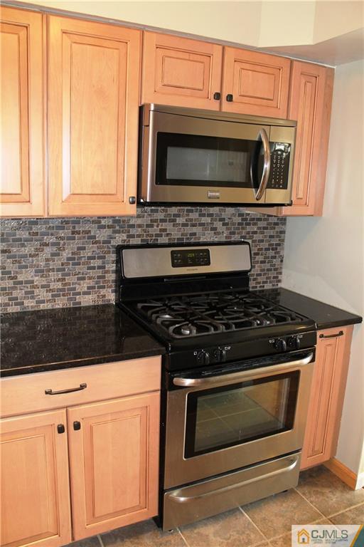59 La Rue Lane, Unit 59 East Brunswick, NJ 08816 - Photo 8 of 17 a kitchen with granite countertop a stove and a microwave