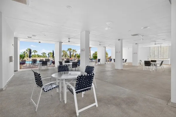 a dining hall with stainless steel appliances a dining table and chairs with kitchen view