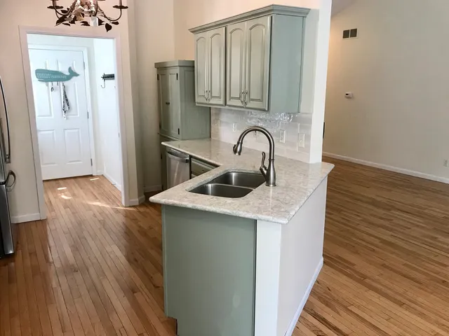 a kitchen with stainless steel appliances a sink and wooden floor