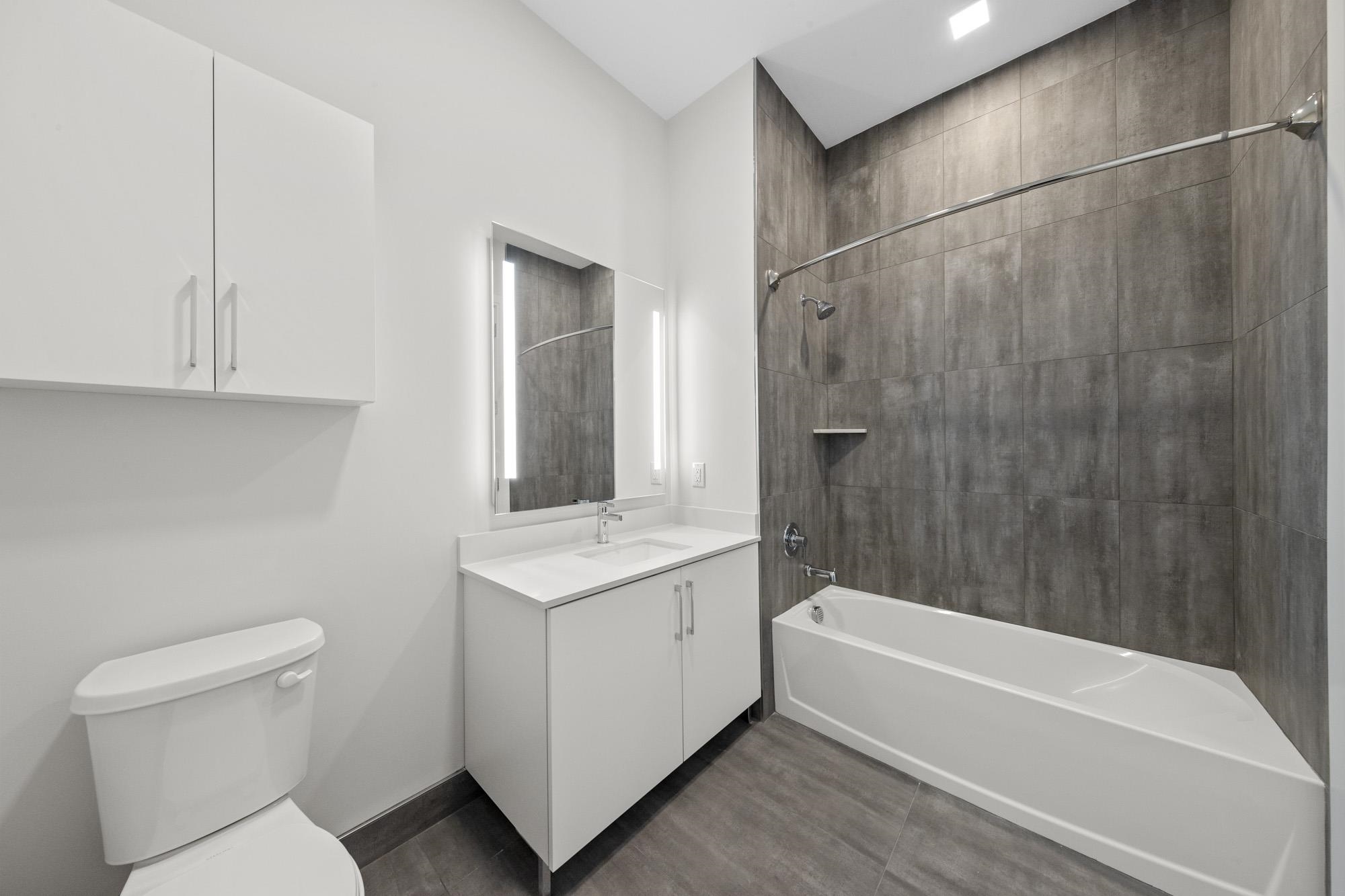 121 34th Street, Unit 415 Union City, NJ 07087 - Photo 11 of 41 a bathroom with a granite countertop sink a toilet and bathtub