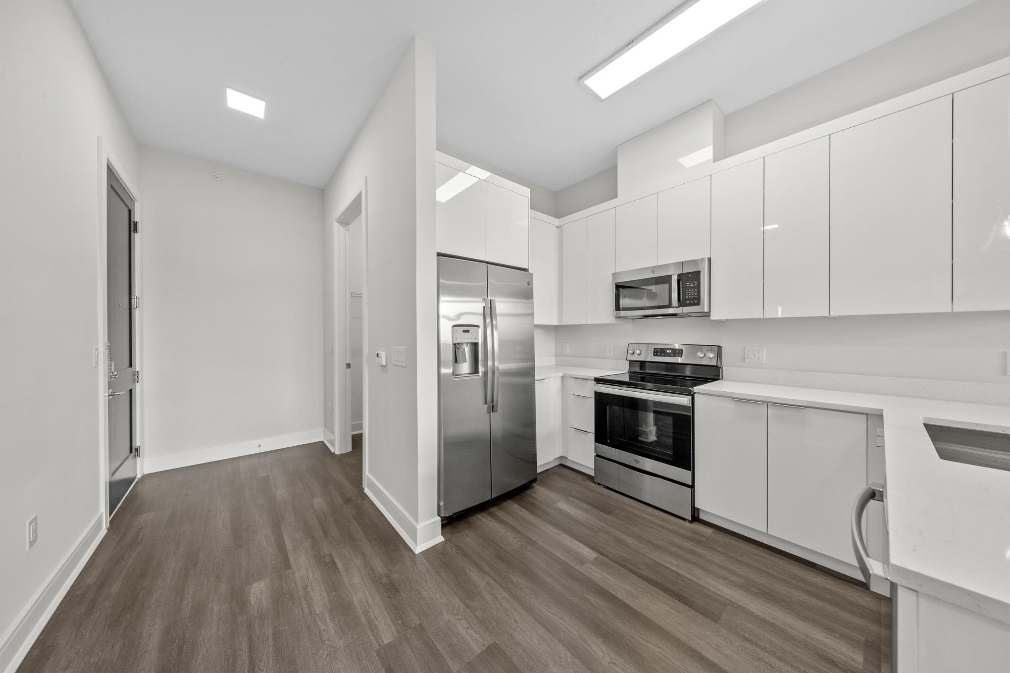 121 34th Street, Unit 415 Union City, NJ 07087 - Photo 2 of 41 a kitchen with wooden floors and stainless steel appliances