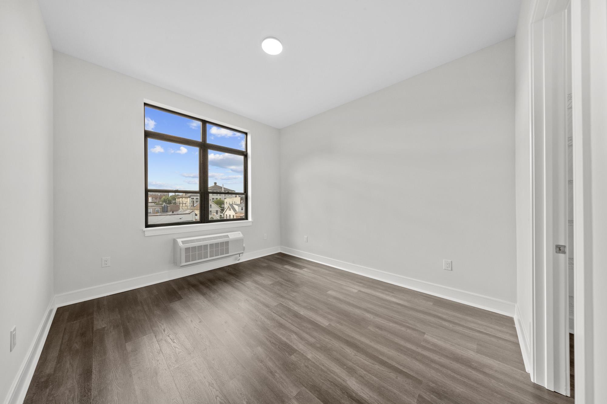 121 34th Street, Unit 415 Union City, NJ 07087 - Photo 8 of 41 an empty room with wooden floor and windows