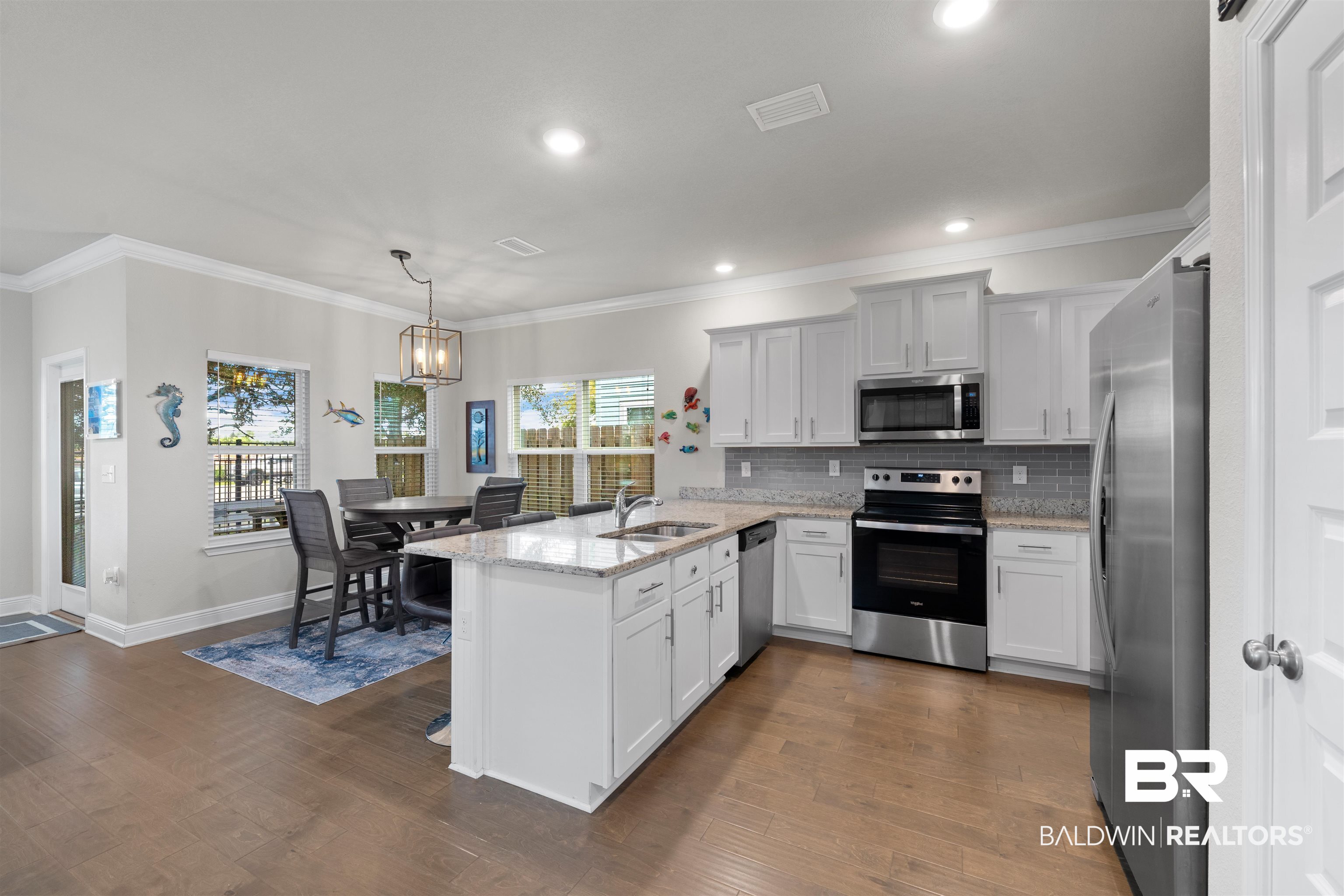 23938 Cottage Loop Orange Beach, AL 36561 - Photo 5 of 24 Kitchen with kitchen peninsula, dark hardwood / wood-style floors, light stone countertops, appliances with stainless steel finishes, and sink