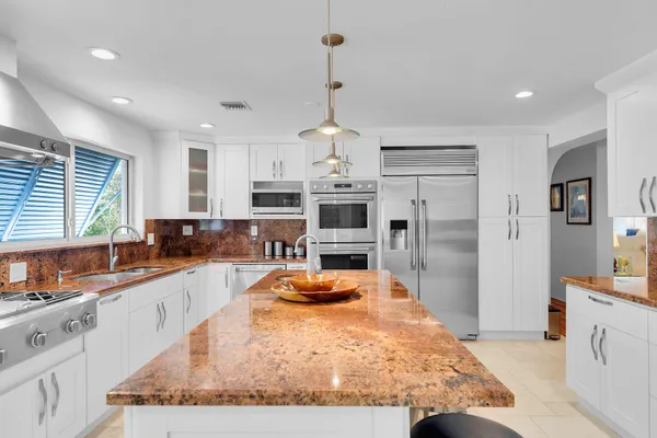 a kitchen with stainless steel appliances granite countertop a sink a stove and a refrigerator