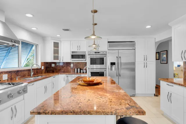 a kitchen with stainless steel appliances granite countertop a sink a stove and a refrigerator