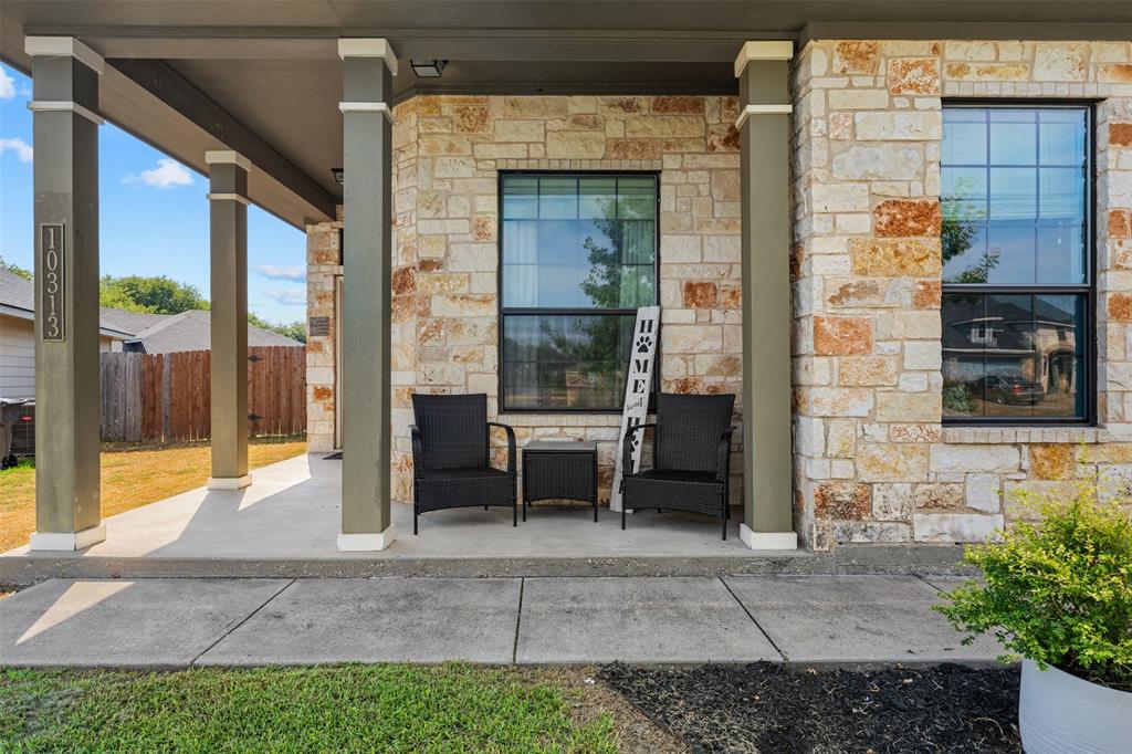 10313 Condor Loop Waco, TX 76708 - Photo 7 of 33 Limestone and brick veneer exterior with a covered concrete porch, multiple square columns, and dark-framed windows
