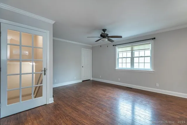 a view of an empty room with a window and wooden floor