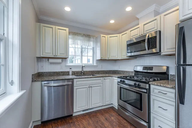a kitchen with stainless steel appliances granite countertop a sink a stove and microwave