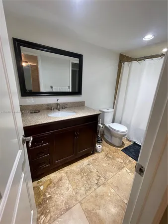 a bathroom with a granite countertop sink toilet and shower