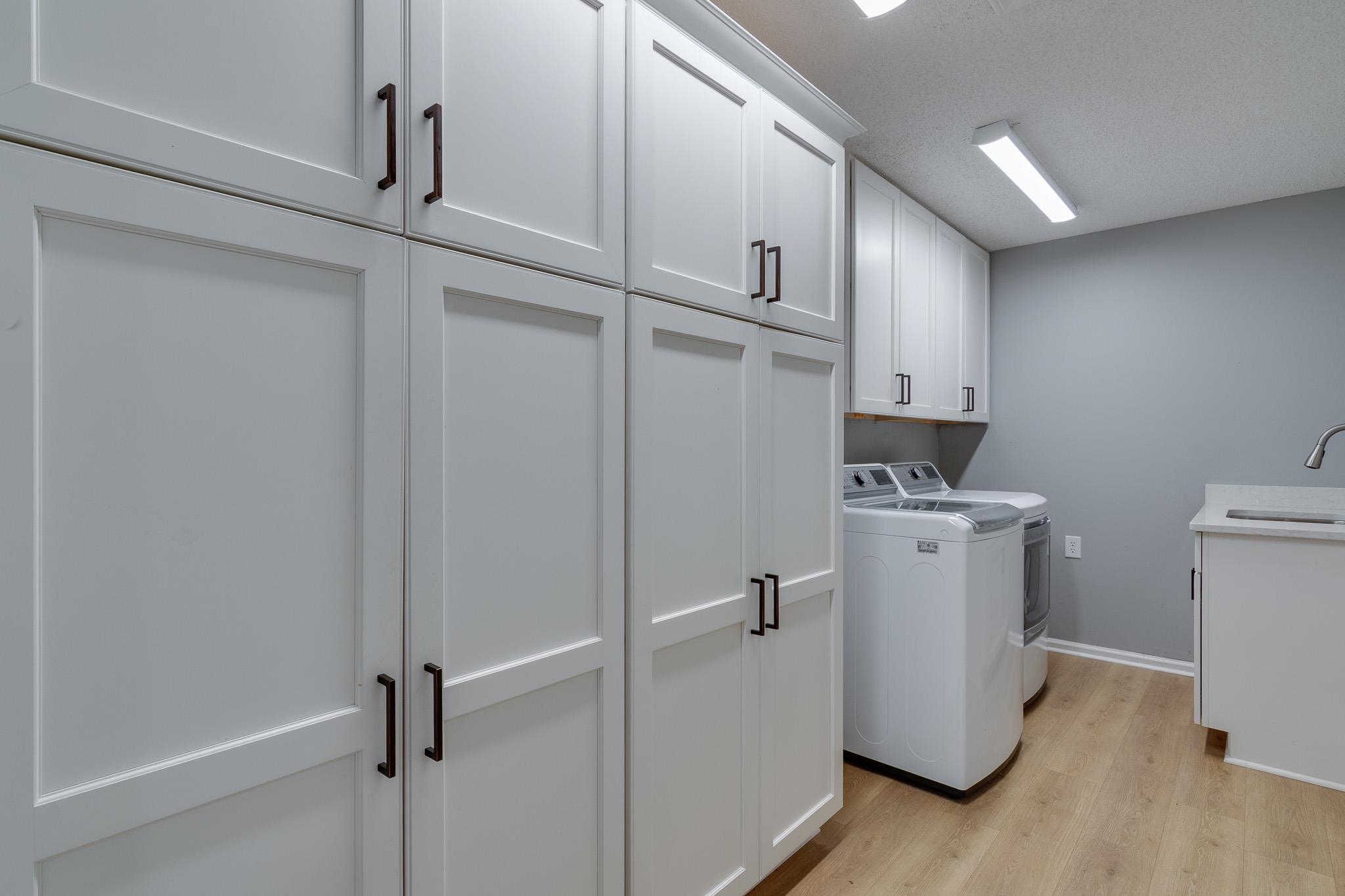 462 Woodbridge Road Somerville, TN 38068 - Photo 23 of 30 Laundry room with cabinet space, washing machine and clothes dryer, and light wood-style floors