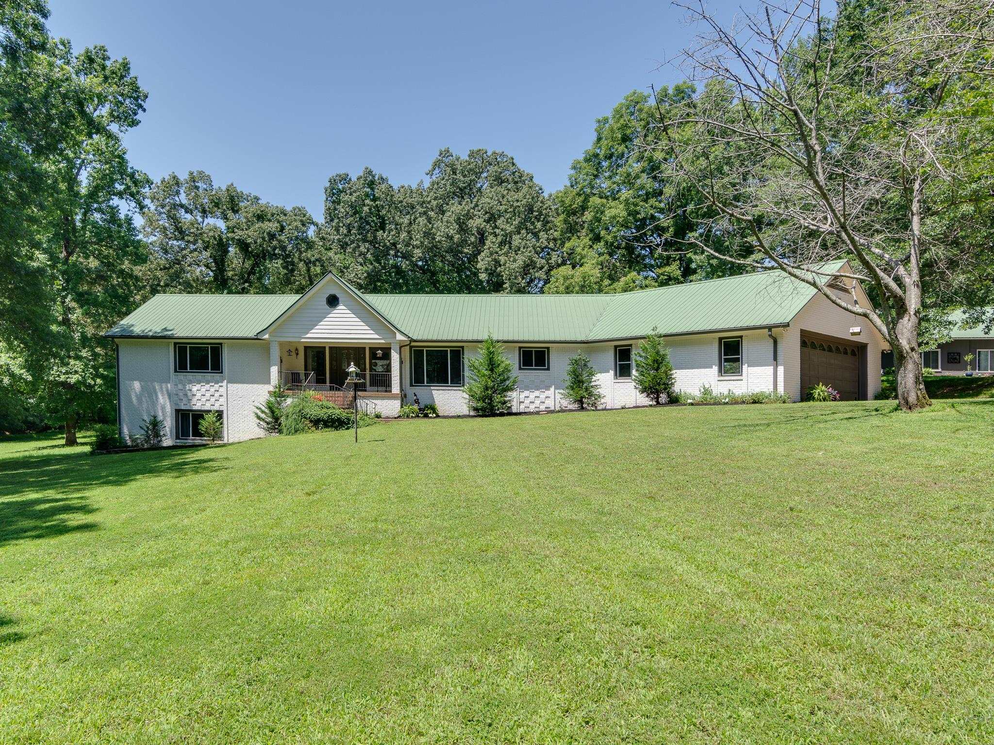 462 Woodbridge Road Somerville, TN 38068 - Photo 10 of 30 Ranch-style house featuring an attached garage, a front lawn, a metal roof, and covered porch