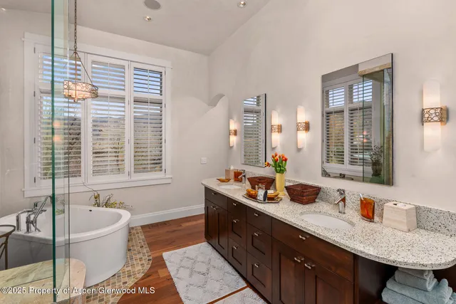 a spacious bathroom with double vanity a window a mirror a bathtub and window