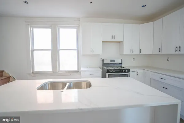 a kitchen with granite countertop a sink a window stainless steel appliances and cabinets