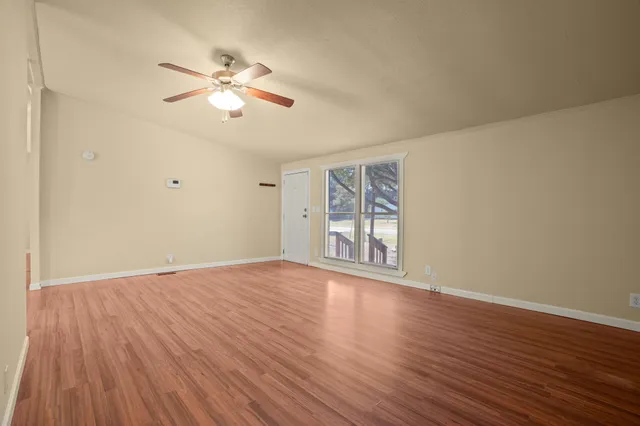 a view of an empty room with wooden floor and a window