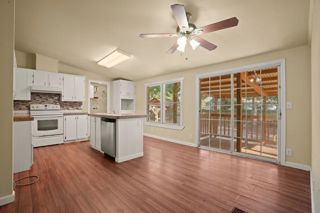 a kitchen with stainless steel appliances wooden floors and white cabinets