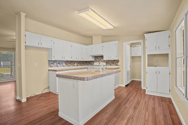 a kitchen with stainless steel appliances granite countertop a refrigerator a sink dishwasher and white cabinets with wooden floor