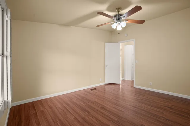 an empty room with wooden floor and ceiling fan