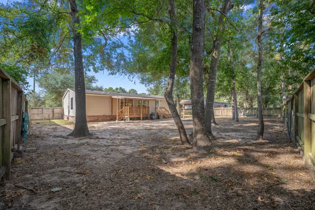 a view of a house with large tree and wooden fence
