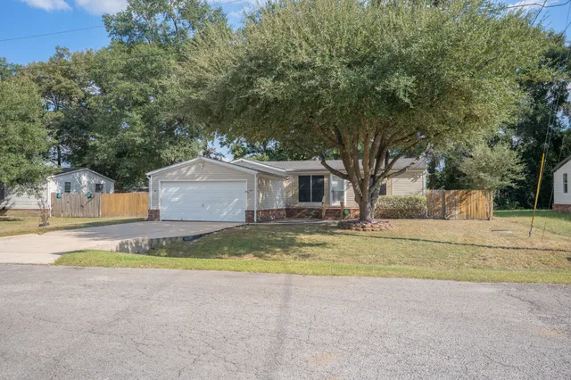 a view of a house with a yard and large tree