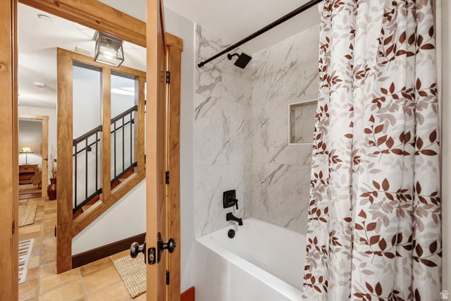 12465 Bone Road Kamas, UT 84036 - Photo 48 of 63 Bathroom featuring marble-look tile surround, integrated bathtub with chrome fixtures, and a decorative shower curtain with leaf motif