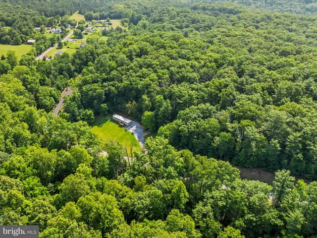 an aerial view of residential house with outdoor space and trees all around