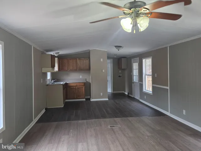 a kitchen with stainless steel appliances granite countertop a refrigerator a sink dishwasher a stove and white countertops with wooden floor