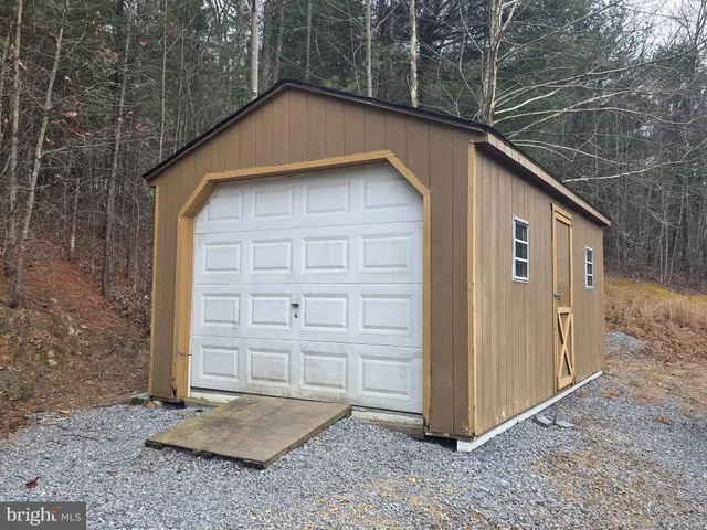 a backyard of a house with large trees and wooden fence