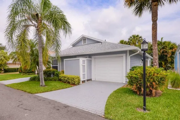 a palm tree sitting in front of a house with a yard