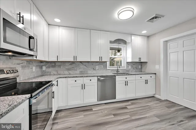 a kitchen with granite countertop cabinets stainless steel appliances and a sink