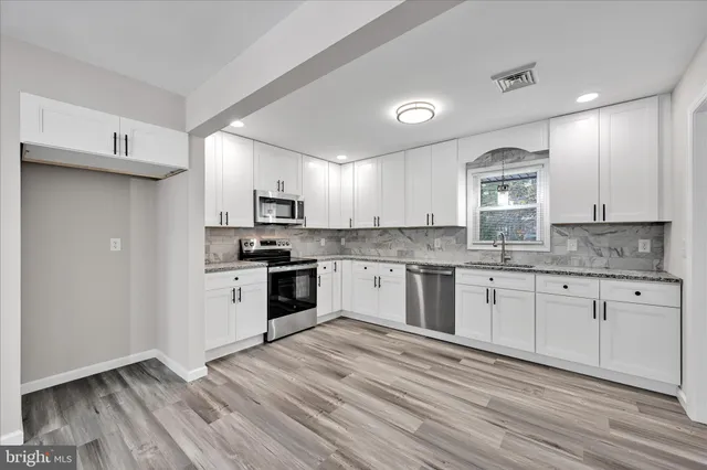 a kitchen with granite countertop white cabinets and stainless steel appliances