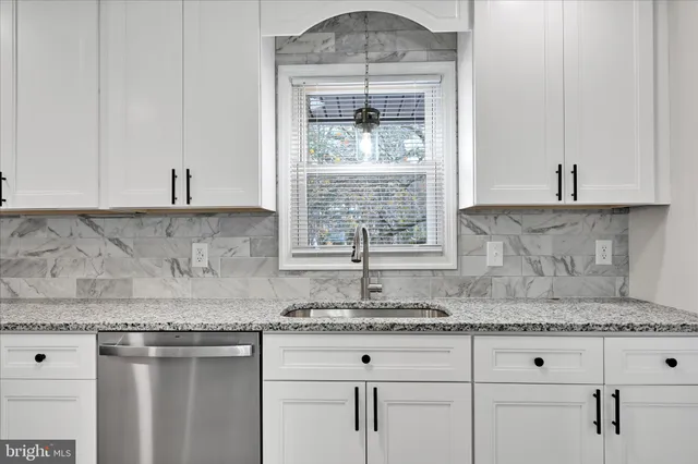 a kitchen with granite countertop white cabinets and a window