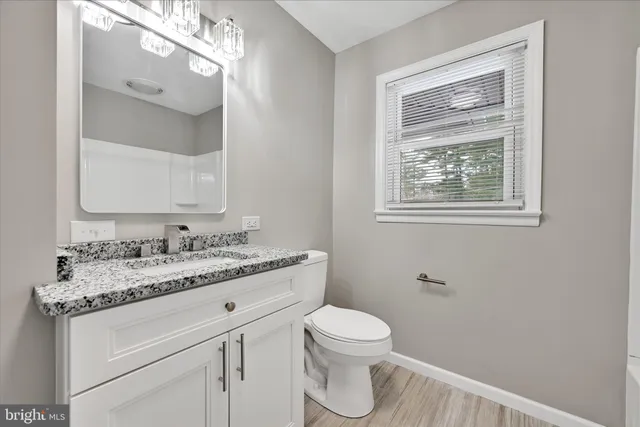 a bathroom with a granite countertop toilet sink and mirror