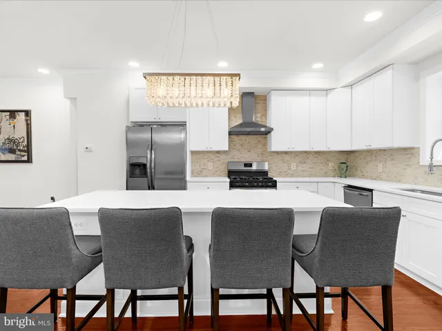 a kitchen with stainless steel appliances granite countertop a dining table chairs and a refrigerator