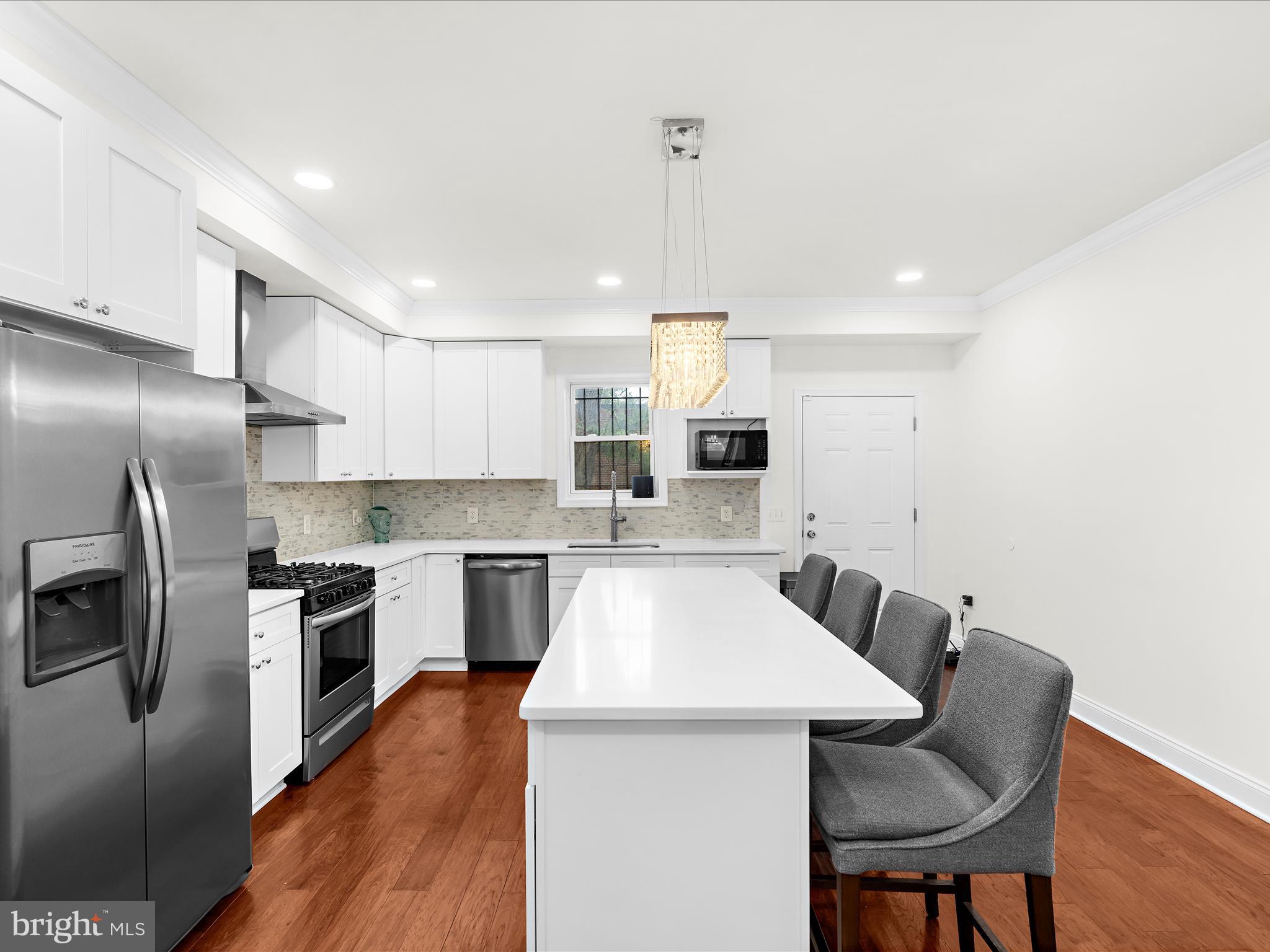 505 Mosher Street Baltimore, MD 21217 - Photo 9 of 46 a kitchen with stainless steel appliances granite countertop a refrigerator a stove top oven a sink dishwasher a dining table and chairs with wooden floor