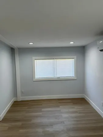 a view of an empty room with wooden floor and window