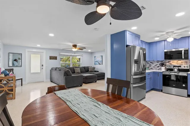 a living room with stainless steel appliances kitchen island granite countertop furniture wooden floor and a window