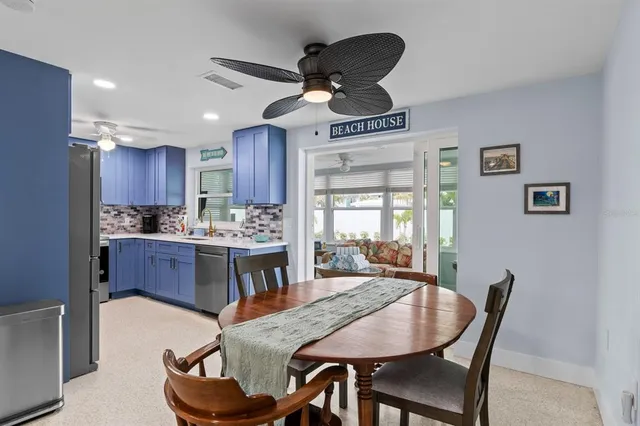 a kitchen with stainless steel appliances granite countertop a stove a refrigerator a sink a dining table and chairs with wooden floor