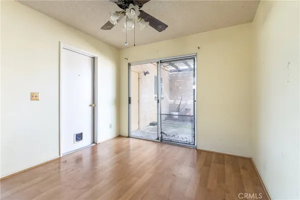 an empty room with wooden floor fan and windows