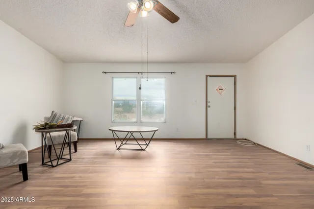 an empty room with wooden floor fan and windows