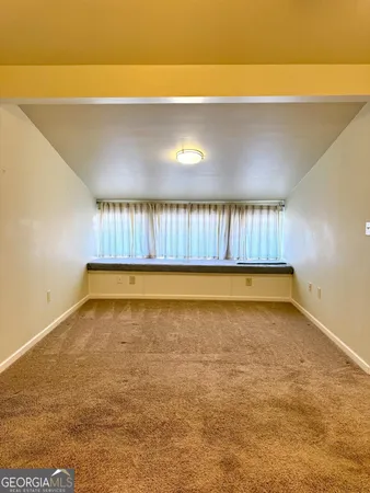 a view of an empty room with cabinet and a window