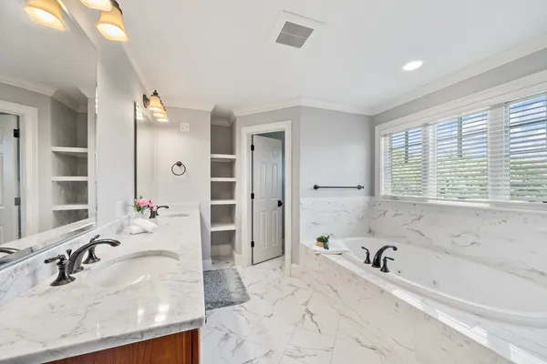 a bathroom with a granite countertop tub sink and mirror