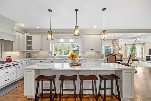 a kitchen with stainless steel appliances kitchen island granite countertop a table chairs and a wooden floor