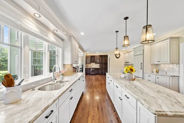 a large kitchen with stainless steel appliances kitchen island granite countertop a sink and wooden floor