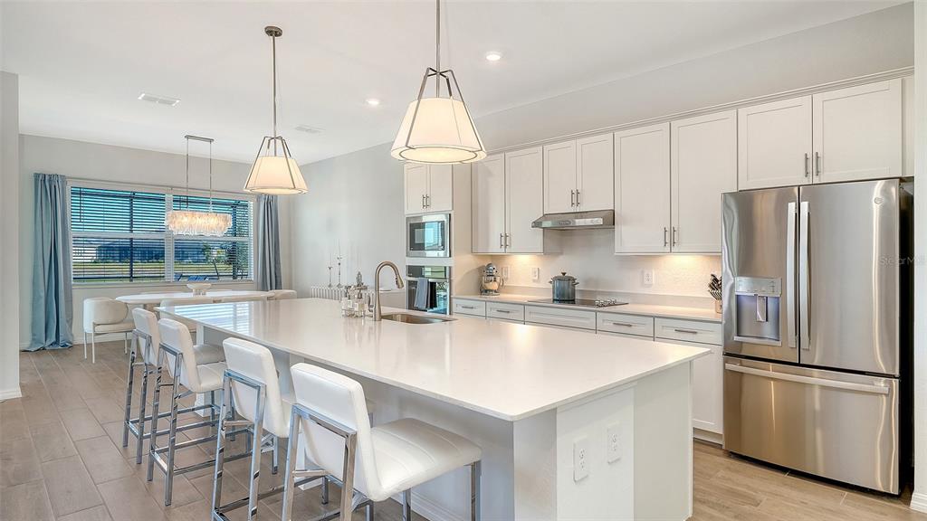17160 Albatross Road Venice, FL 34293 - Photo 13 of 91 a kitchen with stainless steel appliances granite countertop a refrigerator a sink a stove a dining table and chairs
