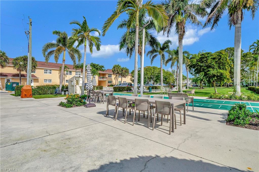 603 12th Avenue South Naples, FL 34102 - Photo 39 of 47 a view of a patio with a table and chairs under an umbrella with palm trees