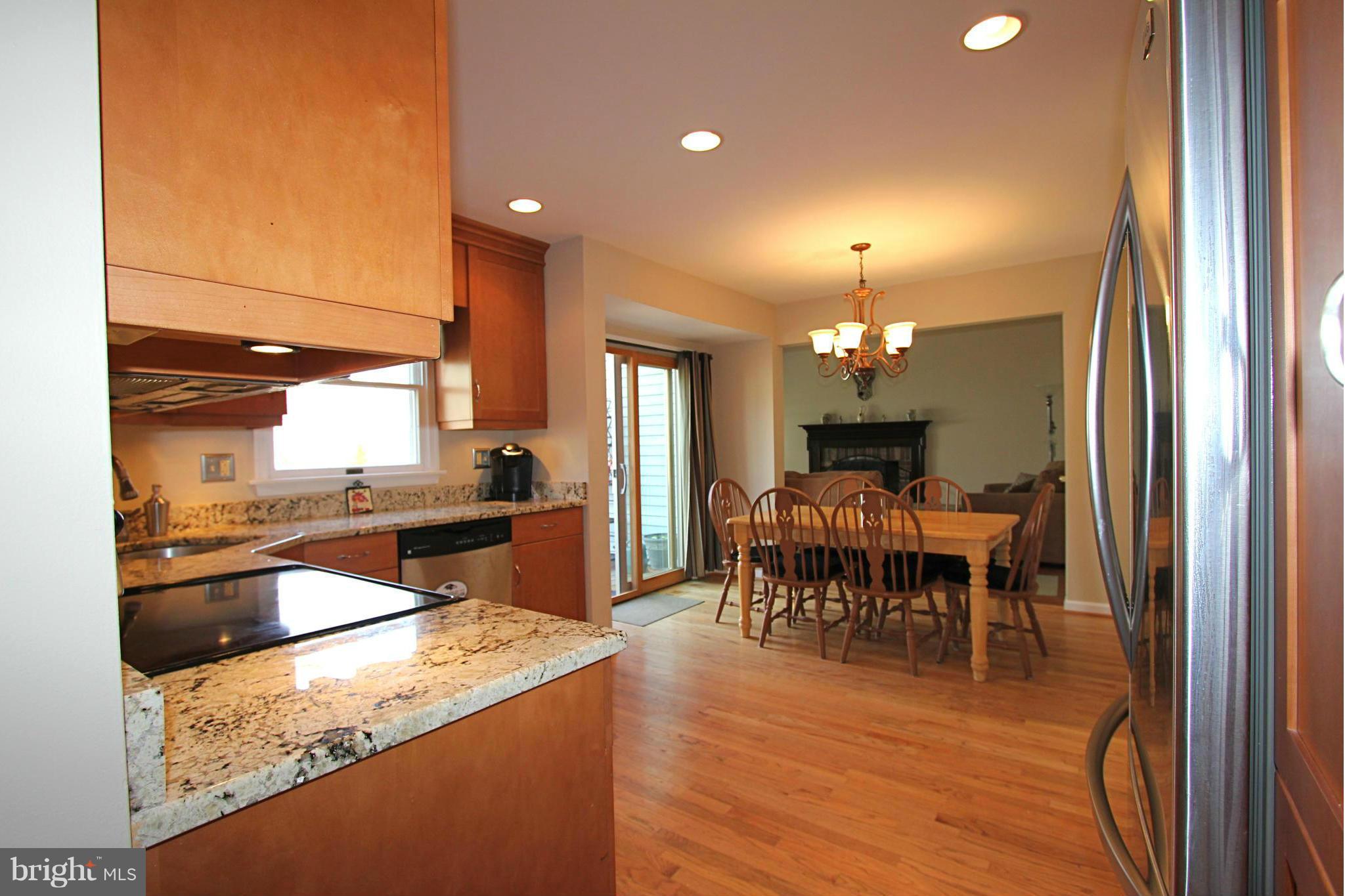 9338 Ramblebrook Road Baltimore, MD 21236 - Photo 7 of 25 a dining hall with stainless steel appliances granite countertop a refrigerator a sink dishwasher a dining table and chairs with wooden floor