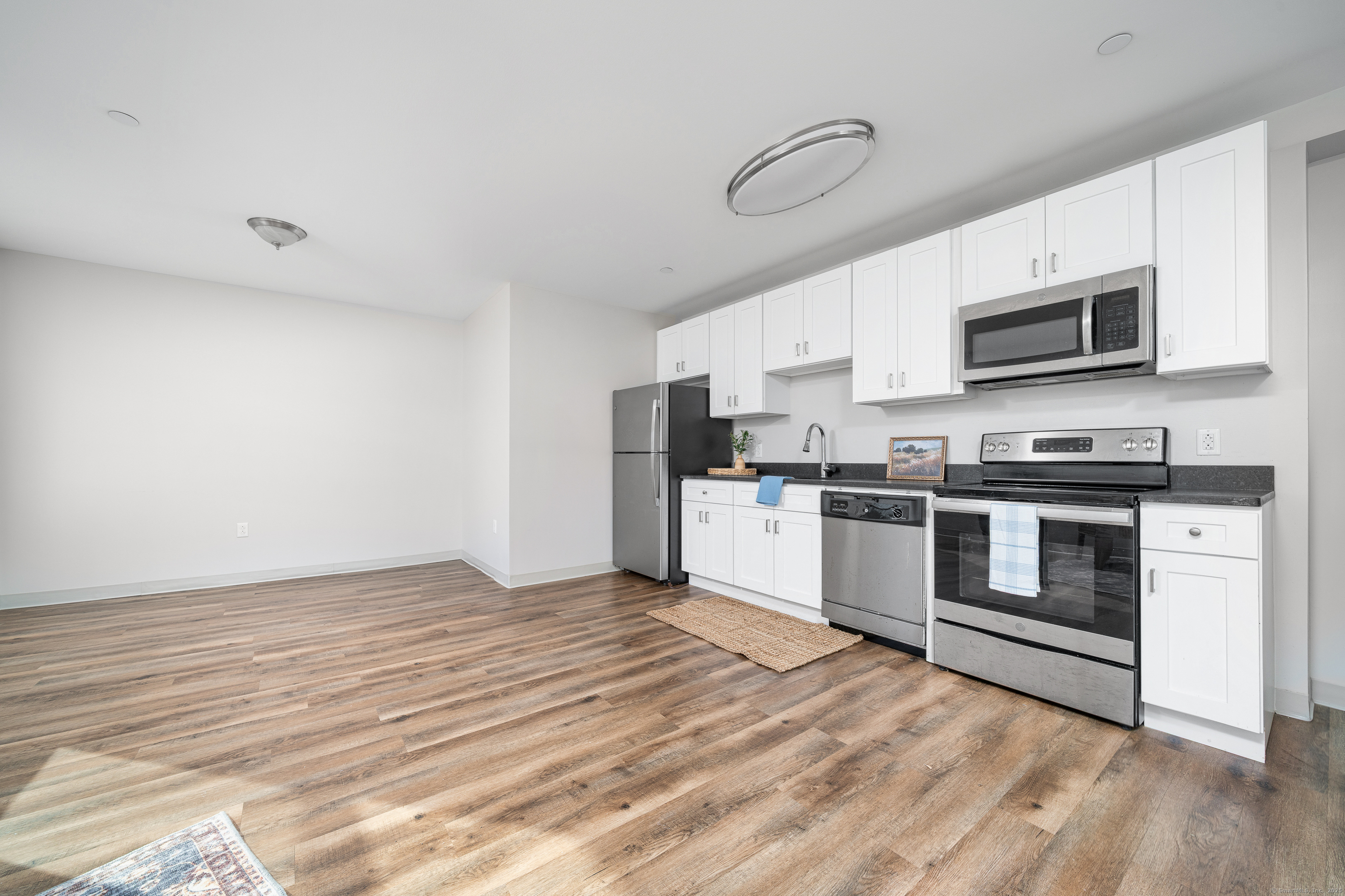 170 Ridge Road, Unit 201 Wethersfield, CT 06109 - Photo 21 of 25 a kitchen with stainless steel appliances a stove top oven a refrigerator white cabinets and wooden floor