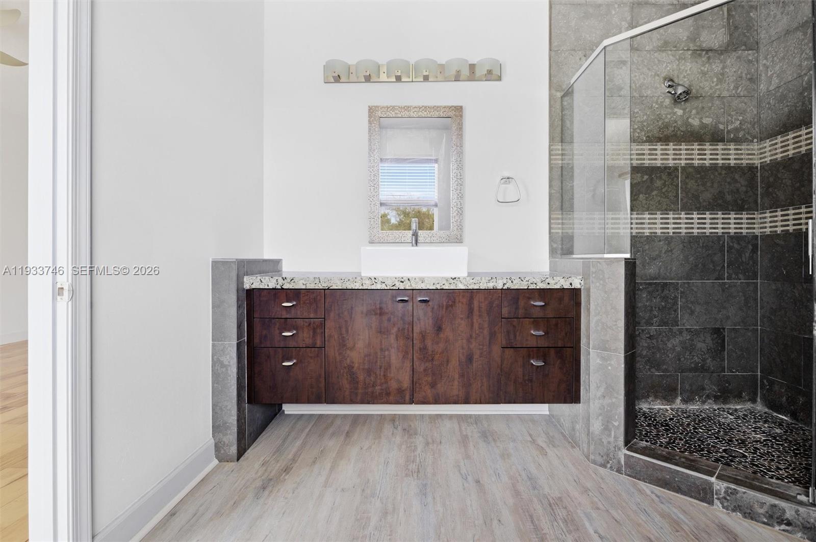 4857 Northwest 16th Terrace Boca Raton, FL 33431 - Photo 11 of 45 a bathroom with a granite countertop sink a mirror and shower