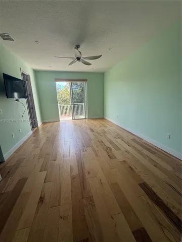 a view of a swimming pool with a patio and a yard with palm trees